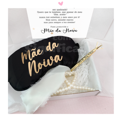 Máscara de dormir preta com texto 'Mãe da Noiva', enfeite dourado 'Bride' e enfeite branco em caixa aberta