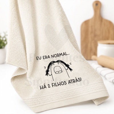 Toalha branca com desenho e texto em português pendurada em ambiente de cozinha