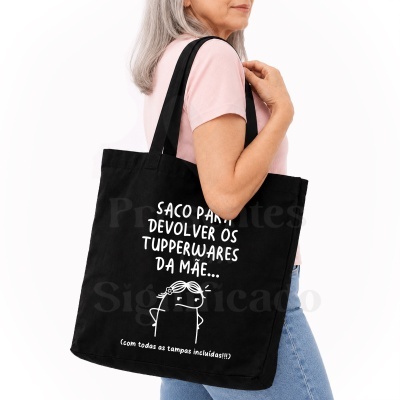 Sacola preta de tecido com texto branco e desenho, usada por mulher com camisa rosa.