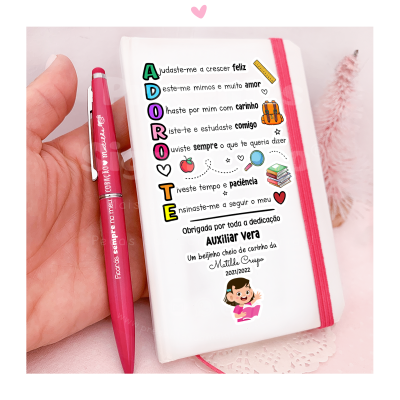 Capa branca para agenda com elástico rosa e texto em português, ao lado caneta rosa com texto, mão segurando ambos