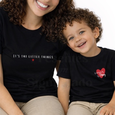 Adulto e criança com t-shirts pretas com texto e coração vermelho, sentados num fundo branco