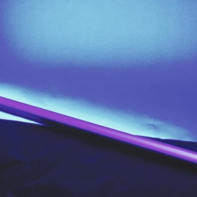 Bastão luminoso roxo sobre superfície preta com fundo azul iluminado