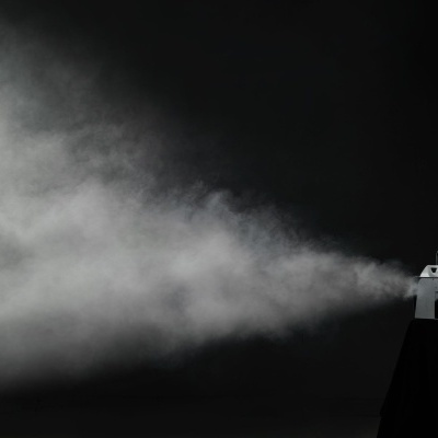 Máquina cinzenta de fumos a emitir fumo amplo contra fundo preto