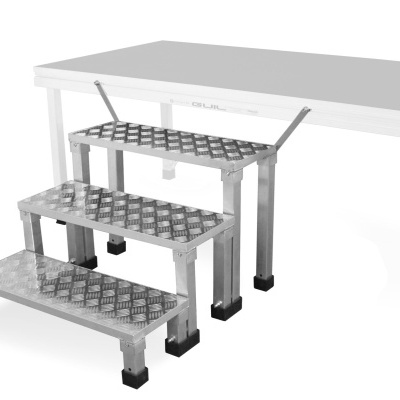 Escada industrial metálica de três degraus com padrão antiderrapante junto a uma mesa branca