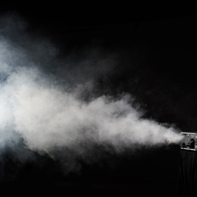 Máquina de fumos preta a emitir fumo branco num fundo preto