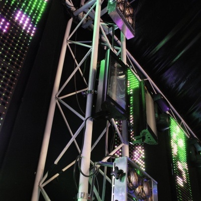 Estrutura metálica com luzes LED verdes e roxas e painéis quadrados em ambiente escuro