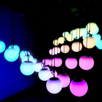 Esferas coloridas penduradas que iluminam num espaço escuro