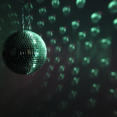 Disco bola prateada pendurada refletindo luz verde