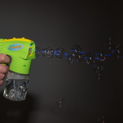 Pistola de bolhas verde com botão amarelo e recipiente transparente