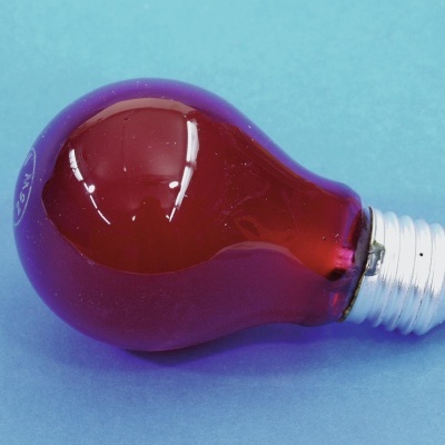 Lâmpada incandescente vermelha sobre superfície azul