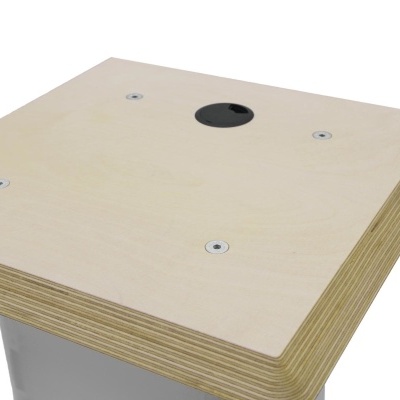 Tampo quadrado de madeira clara com orifício circular preto e quatro parafusos metálicos