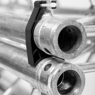 Tubos metálicos cilíndricos com suporte de fixação preto e abraçadeira branca em estrutura metálica