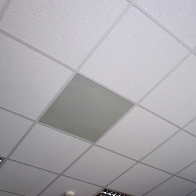 Teto falso modular branco com painel cinza no centro e luminárias embutidas.