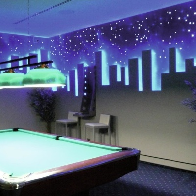 Mesa de bilhar iluminada e parede com pintura luminosa de cidade à noite