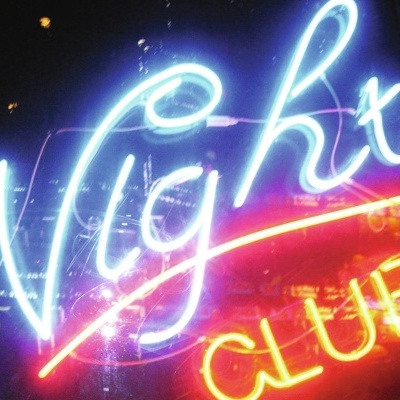 Sinal de néon Night CLUB em azul, vermelho e amarelo numa janela à noite