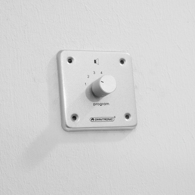 Painel de controlo branco com botão rotativo numa parede branca