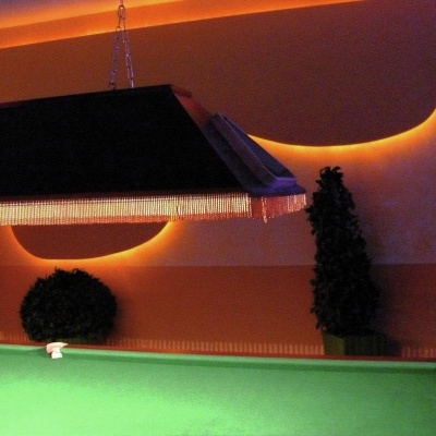 Mesa de bilhar verde com luz pendente e decoração interior com arbustos