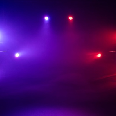 Cenário de palco iluminado com luzes roxas, azuis e vermelhas e névoa