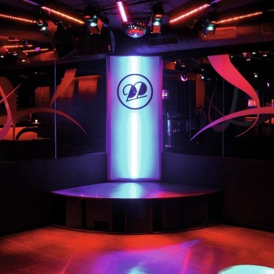 Discoteca com palco iluminado em tons roxos e vermelhos