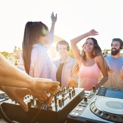 Mesa de DJ profissional e pessoas a dançar ao pôr do sol