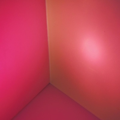 Canto de sala com paredes lisas iluminadas em rosa e laranja