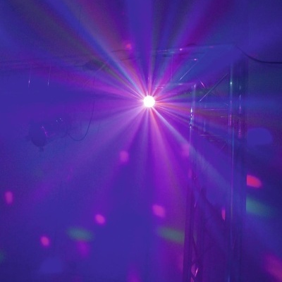 Luz de discoteca colorida com padrões roxos, verdes e rosa numa estrutura metálica