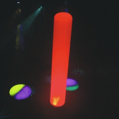 Cilindro luminoso vermelho com projeções de luz colorida ao redor em ambiente escuro