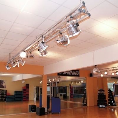 Estúdio de ginásio laranja com espelhos, equipamento de fitness e holofotes no teto