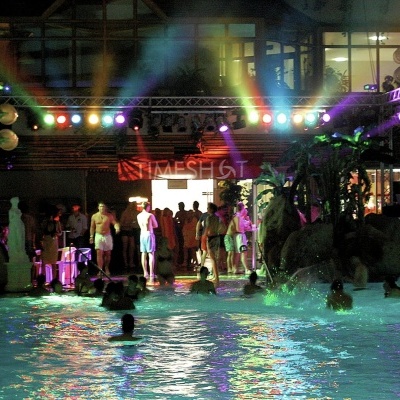 Piscina iluminada à noite com pessoas e luzes coloridas