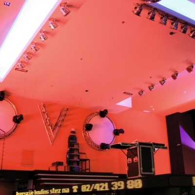 Interior de espaço comercial com iluminação laranja e púrpura e painéis metálicos