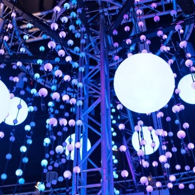 Instalação luminosa com esferas penduradas em luz azul e roxa