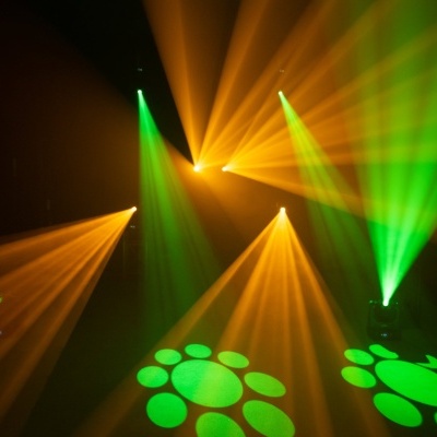 Luzes de palco verdes e laranjas projetando padrões circulares.