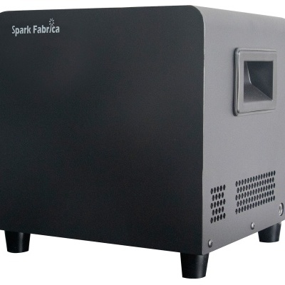 Caixa cúbica preta com a inscrição Spark Fabrica e ventilação lateral.