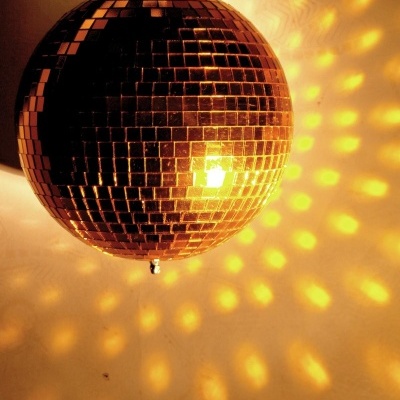 esfera espelhada suspensa com iluminação amarela projetando reflexos na parede