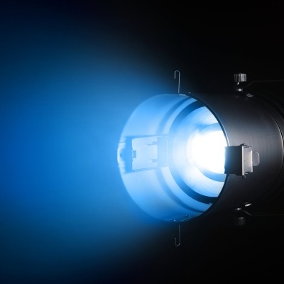 Projetor de luz preto emitindo feixe de luz azul intensa