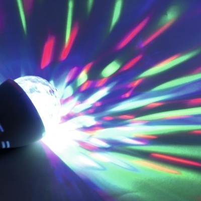 Dispositivo luminoso em forma de bola com base preta a criar projeção colorida na parede