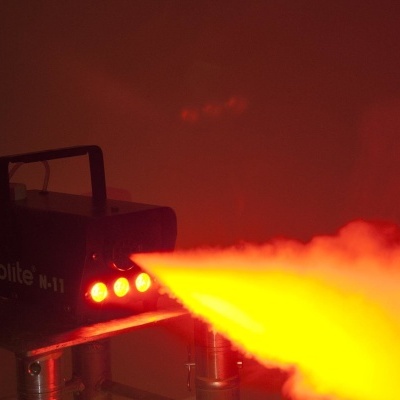 Máquina de fumo preta a emitir fumo iluminado em laranja