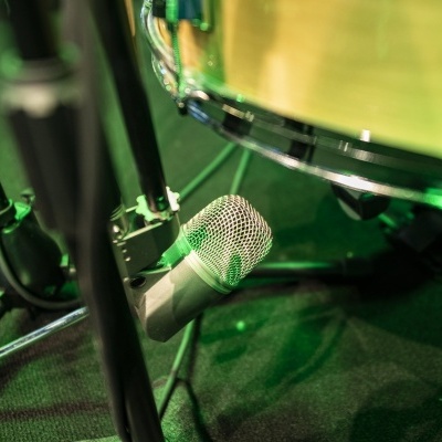 Microfone prateado junto a tambor de bateria com iluminação verde