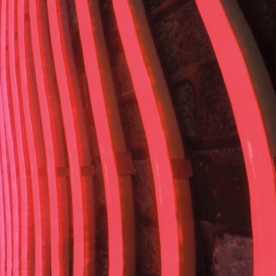 Tubos de néon rosa alinhados numa parede de tijolos