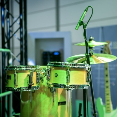 Timbales metálicos verdes com microfone e guitarra elétrica verde ao fundo