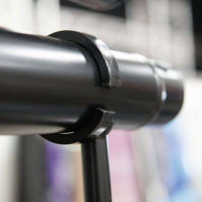 Tubo metálico prateado com suportes pretos em fundo desfocado