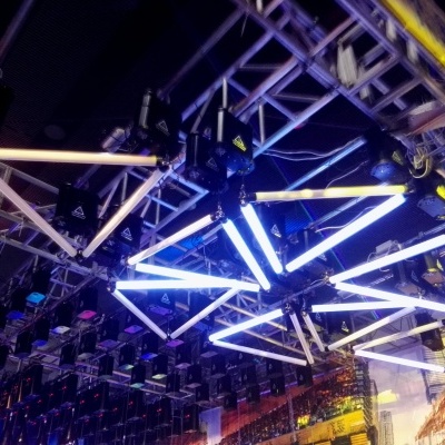 Tubos de luz LED brancos e azuis suspensos formando padrão geométrico em estrutura metálica