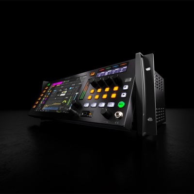 Equipamento eletrónico preto com ecrã digital colorido e botões iluminados sobre fundo escuro