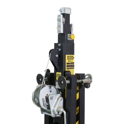 Elevador de carga industrial preto com manivelas metálicas e etiquetas amarelas