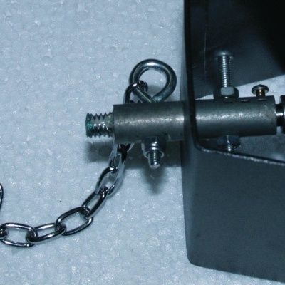 Dispositivo metálico preto com corrente prateada numa superfície branca