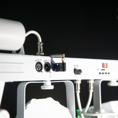 Equipamento de áudio branco com botões, interruptores e conexões em fundo escuro