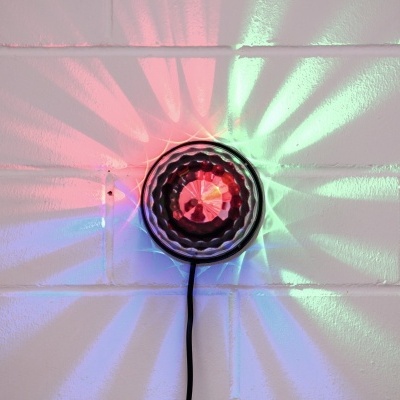 Luz decorativa redonda com padrões de luz colorida na parede branca