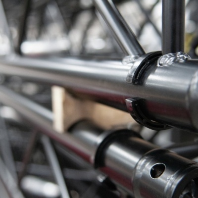 barras metálicas cilíndricas prateadas com anéis pretos e fundo industrial desfocado