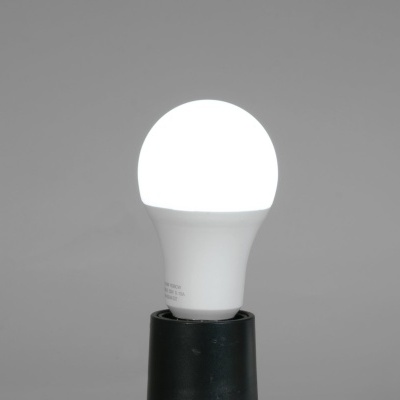 Lâmpada LED branca montada num suporte preto sobre fundo cinzento