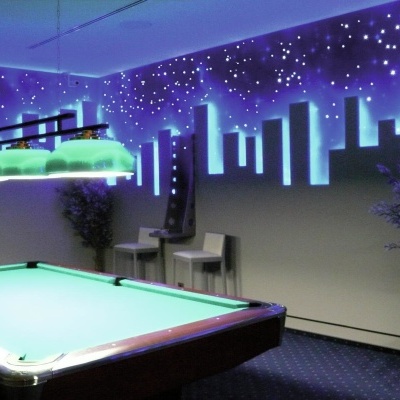 Mesa de bilhar verde com iluminação e mural urbano azul